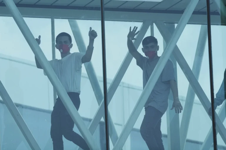 Two men walking across a sky bridge